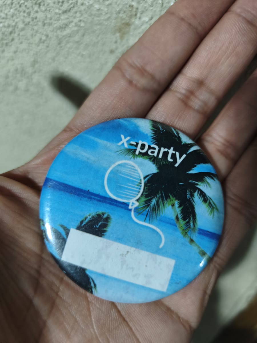 x-party pin with palm trees and beach in hand, souvenir from the Rosarito camping trip